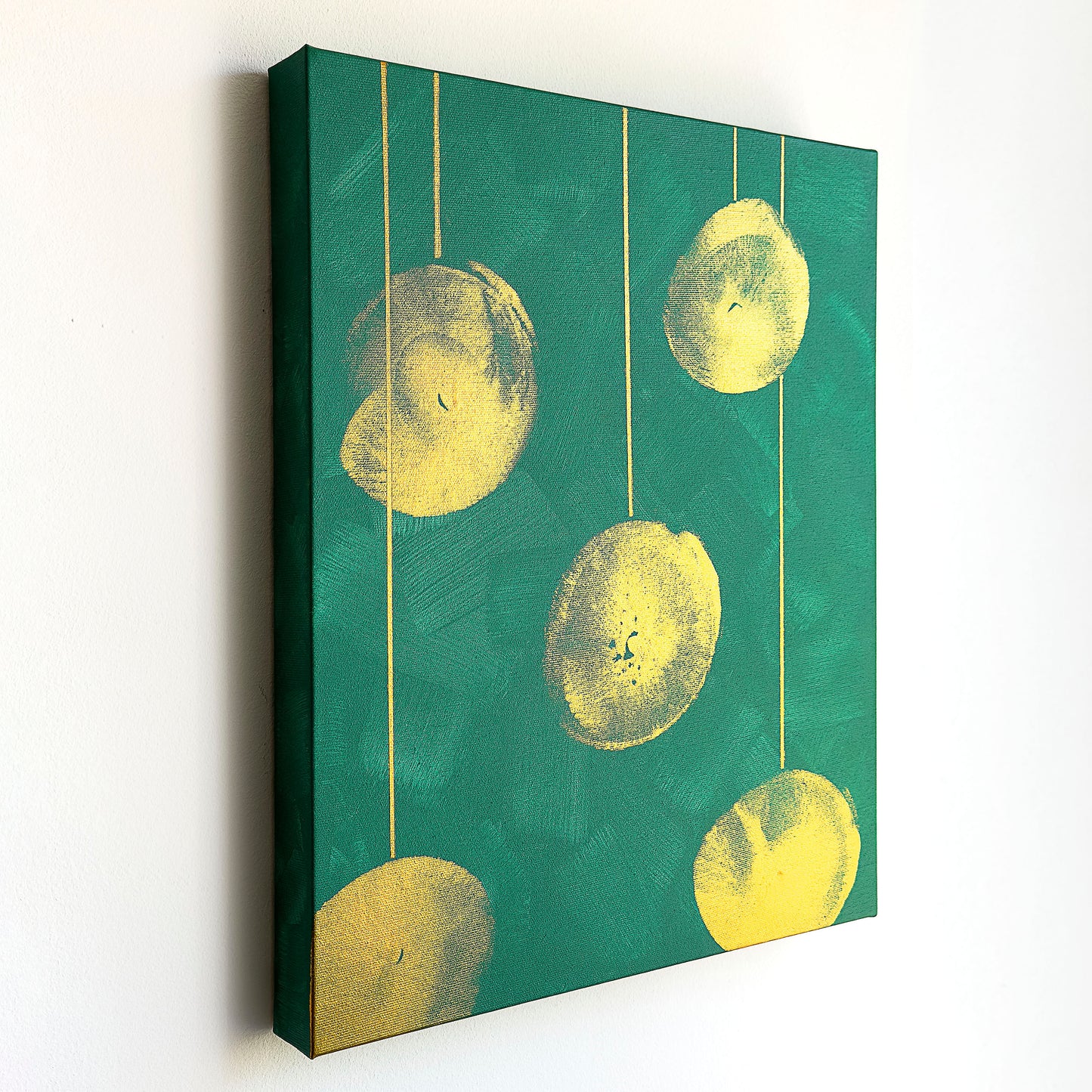 Perspektivische Aufnahme vom Kunstwerk BC #05 Acrylfarbe auf Leinwand. Das Kunstwerk zeigt fünf Lampions in goldener Farbe auf einem türkisfarbenen Hintergrund. Die Lampions wurde mit der Brust gestempelt und hängen jeweils an einer geraden goldenen Schnur.